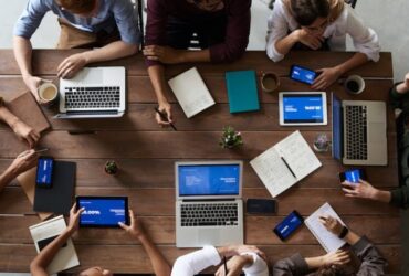 Emprendedores reunidos con portátiles en mesa de madera